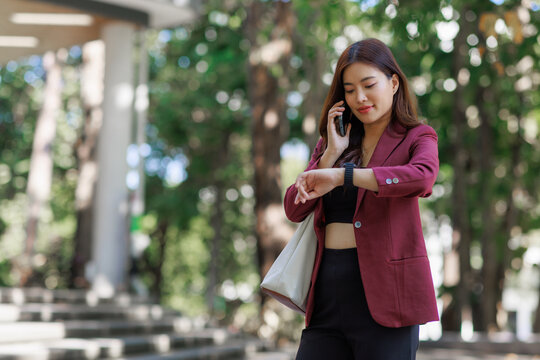 Busy young woman managing time using smartphone and smartwatch