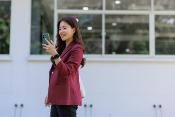 Young asian woman smiling using mobile phone outdoors
