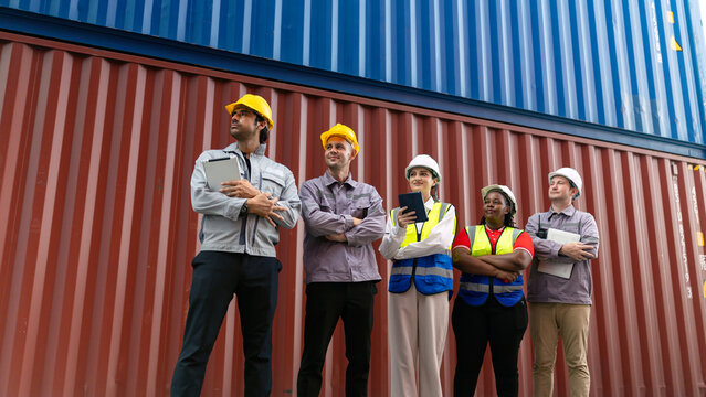 Diverse logistics and engineering team standing confidently in front of shipping containers. Concept of teamwork, global trade, industry, and supply chain management - Powered by Adobe
