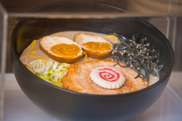 Close-up of a bowl of Japanese ramen with sliced pork, soft boiled eggs, narutomaki, seaweed, scallions, and noodles in broth