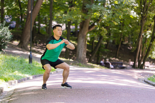 Asian young man runner sportsman male athletic trainer in good physical shape doing warm-up morning sport exercises, yoga gymnastic stretching muscles avoid body tension healthy lifestyle in park. - Powered by Adobe