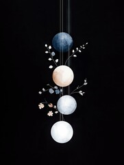 Four spheres of varying colors and textures hang vertically, adorned with delicate branches and small flowers, set against a solid black background.