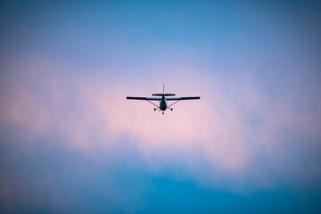 Small single-engine airplane flying against a dramatic cloudy sky at dusk, symbolizing adventure and freedom in aviation