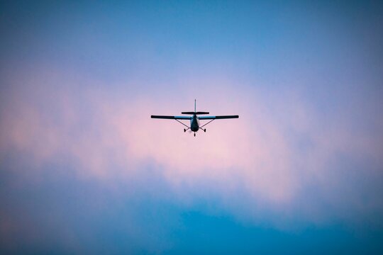 Small single-engine airplane flying against a dramatic cloudy sky at dusk, symbolizing adventure and freedom in aviation