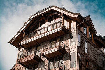 Traditional wooden chalet with multiple balconies under a partly cloudy sky showcasing rustic alpine architecture