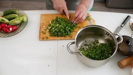 Chef chopping green onions and adding to pot