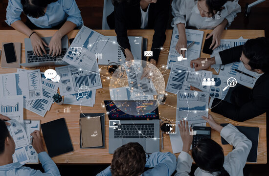 A diverse team of professionals engages in a collaborative meeting, surrounded by data charts and technology, illustrating effective teamwork and communication in an office setting. Trope