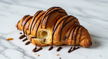 Delicious chocolate drizzled croissant on marble surface