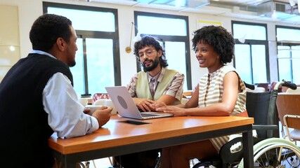 Diverse coworkers discussing project with disabled colleague - Powered by Adobe