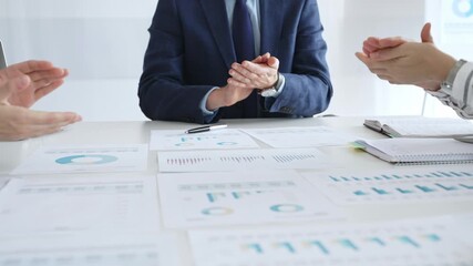 Businesspeople team clapping hands in meeting celebrating success with financial charts, data analysis, sales growth reports, and teamwork achievement in modern office. Business handshake - Powered by Adobe