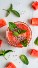 Top view of watermelon smoothie with chia seeds and fresh mint leaves on white marble background