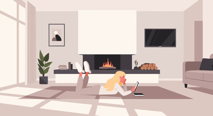 A blonde woman relaxing on the floor with a laptop in a cozy living room with a fireplace and sunlight.