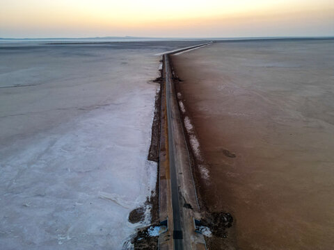 Aerial view of the endless road cutting through the white desert of the Rann of Kutch, captured during golden hour.