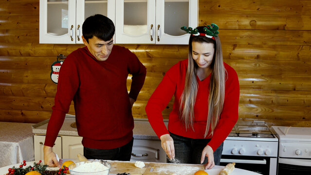 The couple joyfully bakes Christmas cookies together, rolling out dough . - Powered by Adobe