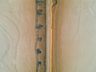 Aerial view of Dholavira’s cracked salt desert and narrow earthy trail, showcasing striking...