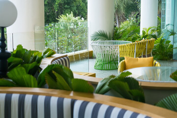 Modern outdoor seating area with colorful woven chairs and lush green tropical plants in a relaxing garden setting