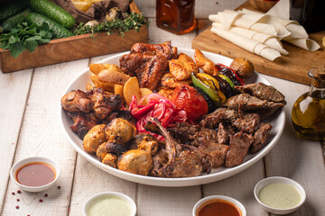 Platter with assorted kebab shashlyq meats grilled vegetables potatoes and sauces