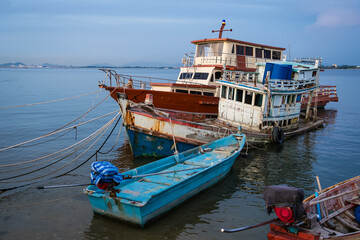 Traditional wooden fishing boats docked in a calm harbor with ropes and nets visible during a peaceful seaside day