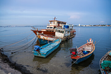 Fototapeta premium Traditional wooden fishing boats docked in a calm harbor with ropes and nets visible during a peaceful seaside day