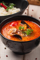 Aromatic spicy tom yam soup with mussels shrimp mushrooms and herbs paired with rice bowl