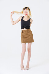 Asian beauty attractive woman blonde long hair stand wear black sleeveless top brown short skirt on white background studio portrait fashion street outfit trendy style pose look at camera full length.