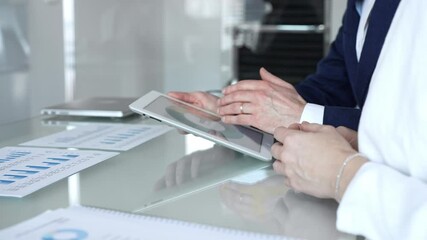 Business partners collaborating on financial data, discussing market trends, analyzing charts, and reviewing reports on a tablet in an office meeting setting - Powered by Adobe