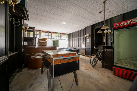 Abandoned lakeside holiday resort with deserted wooden cabins, overgrown vegetation, and decaying buildings reclaimed by nature