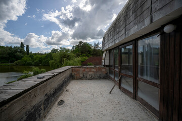 Obraz premium Abandoned lakeside holiday resort with deserted wooden cabins, overgrown vegetation, and decaying buildings reclaimed by nature