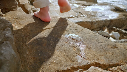 Feet step on rocky terrain, casting a shadow. The scene evokes mindfulness and reflection, suggesting a journey or escape.