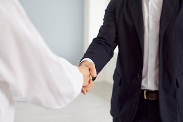 Fototapeta premium Strong handshake between a business man and a business woman, close-up. Concept of workplace agreement, company negotiations. Partnership in business. Group of colleagues, respect