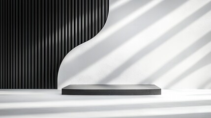 A dark, rectangular podium sits on a white surface, set against a backdrop of a black ribbed wall and a white wall with diagonal shadow lines.