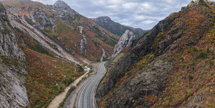 Aerial view of the A1 motorway winding through steep autumn-coloured mountains in the Mirdite district of northern Albania.
