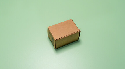 Small brown cardboard box centered neatly on a mint green surface.