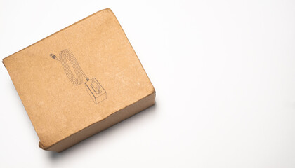 A brown cardboard box featuring a black line art illustration of a coiled cable and connector. It rests diagonally on a pure white background with copy space.