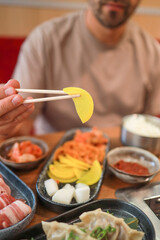 A man eats kimchi, banchan, and other Korean appetizers with chopsticks in a restaurant. Fermented food, traditional Asian meals