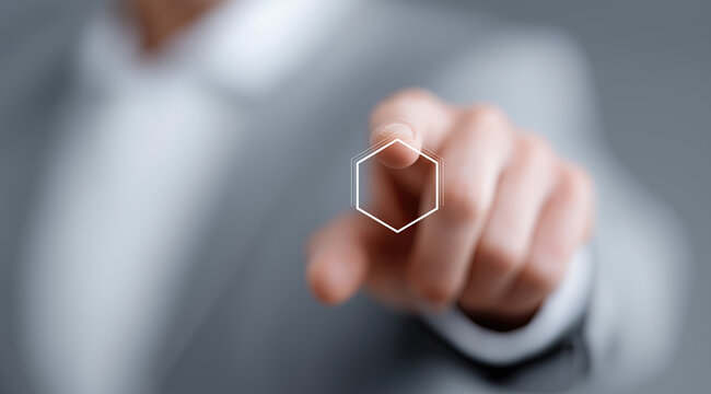 Professional hand touches glowing hexagonal interface displaying futuristic digital technology concept.