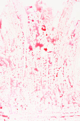 A light surface is covered with an abstract texture of faded and streaked red liquid or food...