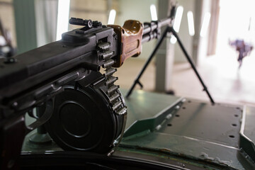 Close up view of a Soviet RPD Degtyaryov machine gun with an ammo belt loaded with bullets mounted on a green armored vehicle inside a hangar ready for a dangerous battle combat war defense