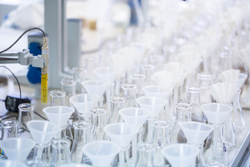 Rows of glass Erlenmeyer flasks with plastic funnels and white paper filters stand on the table ready for chemical analysis filtration process in the modern scientific laboratory room