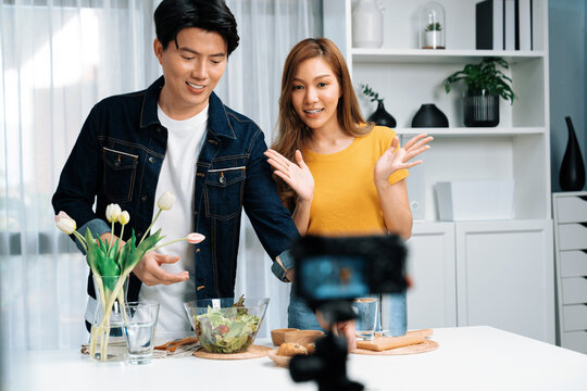 Cooking show on live streaming with two chef influencers presenting wholegrain bun bread side dish with mix salad preparing ingredients with dressing for easy special menu record by camera. Infobahn.