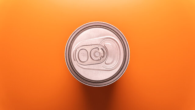 An overhead close-up shot of the silver aluminum beverage can lid, featuring the iconic ring-pull tab on a bright orange surface.