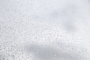 Raindrops on a Glass Surface – Minimalist Macro Background,A close-up image of raindrops clinging to a glass surface against a soft gray, cloudy background. The minimalist and calm composition highlig