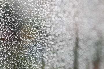 Abstract Raindrops and Bokeh Light Circles – Artistic Macro Texture,An artistic macro photograph featuring raindrops on a glass surface combined with bright bokeh light circles on the right 