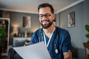 Male nurse or doctor smiling and reading documents at home