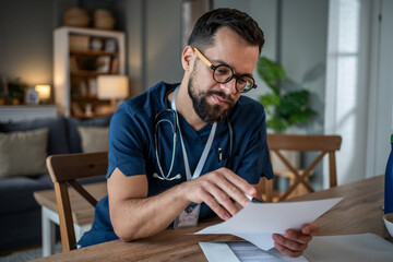 Fototapeta premium Male nurse reviewing medical documents during home visit