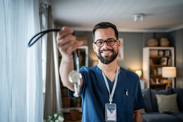 Male doctor offering stethoscope during home medical visit