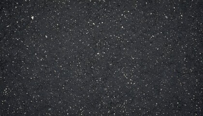 Close-up view of a dark, textured surface with numerous small, light-colored specks, resembling granite or asphalt.