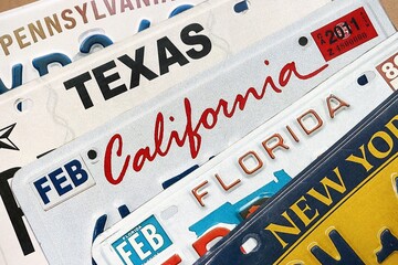 Old US car license plates with various state names close up. Concept of driving in United States. Reaching a car registration