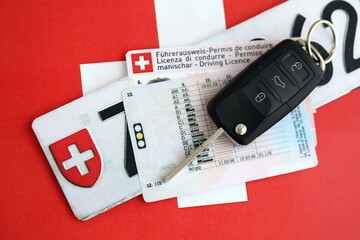 Switzerland car license plate and ignition key on Swiss flag close up. Driving permit and...
