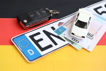 Germany Deutschland car license plate and ignition key on german flag close up. Driving permit and registration concept